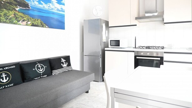 Eine moderne Küche mit Kühlschrank, Mikrowelle, Herd und einem Essbereich mit einer Couch.