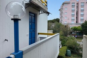 Ein Gebäude mit einer blauen Tür, einem Balkon mit geländer und einem klaren Himmel.