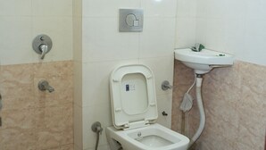 A bathroom with a toilet, a sink, and a shower head. - Hotel Hari sarovar (Kurukshetra)