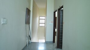 A hallway with a tiled floor, a ceiling light, and a door at the end. - Hotel Hari sarovar (Kurukshetra)