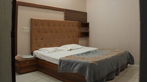 A bedroom with a bed, a nightstand, a ceiling fan, recessed lighting, and a tiled floor. - Hotel Hari sarovar (Kurukshetra)