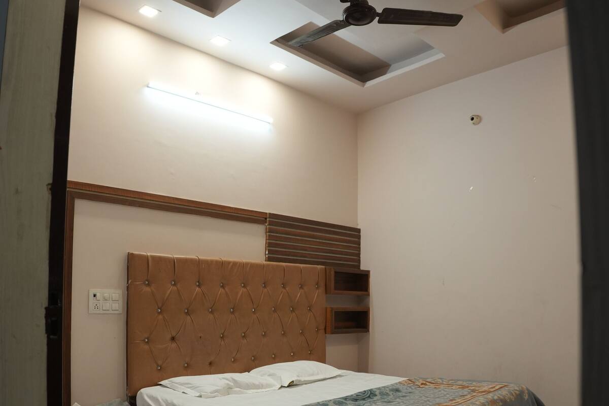 A bedroom with a bed, a nightstand, a ceiling fan, recessed lighting, and a tiled floor.