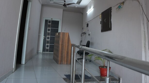 A modern hallway with a staircase, a reception desk, and a ceiling fan. - Hotel Hari sarovar (Kurukshetra)