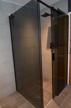 A glass-enclosed shower area with a tiled floor and a wooden door. - Roan's Lodge – Surrounded by nature - Close to Örebro (Frövi)
