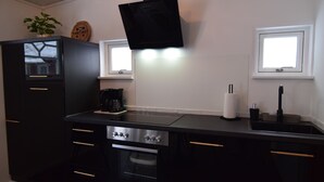 Uma cozinha moderna com armários pretos, forno embutido, cafeteira e janela sobre a pia.
