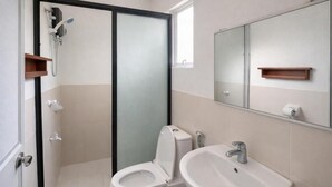 A bathroom with a shower enclosure, toilet, sink, and a mirror. - ISLO APT (General Luna)
