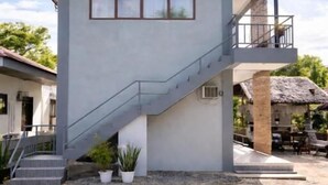 A modern building with a staircase, a balcony, and a small garden area. - ISLO APT (General Luna)