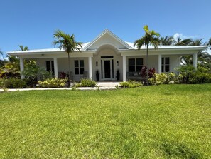 A two-story house with a covered porch, a front door, and a well-maintained lawn. - Sunnyside is directly across from the sand bar on beautiful Treasure Cay beach. (Treasure Cay)