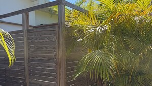 Una estructura de pergola de fusta amb un sòl de grava i vegetació circumdant.