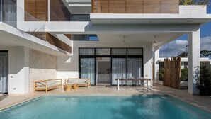 Une maison moderne dotée d’une piscine, d’un espace salon extérieur et d’un patio couvert.