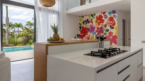 Une cuisine moderne dotée d’un îlot central, d’un coin repas et offrant une vue sur une piscine.
