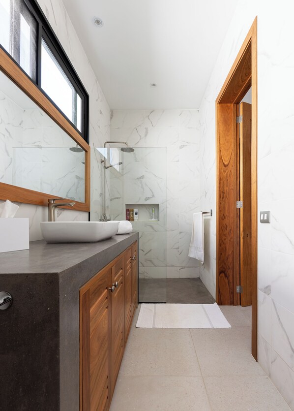 Une salle de bain moderne avec un grand miroir, un lavabo, une douche et une porte en bois.
