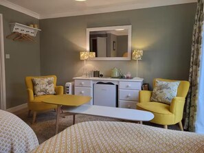 A hotel room with two yellow armchairs, a small white table, a kitchenette, a mirror above the counter, and a bed with patterned bedding. - 2bed-sleeps4-petsok-courtyard & Garden (Totnes)