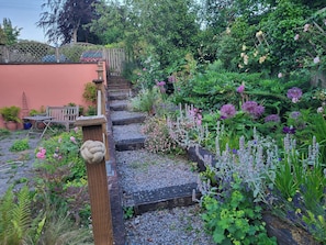 A garden with a wooden staircase, a bench, and various plants. - 2bed-sleeps4-petsok-courtyard & Garden (Totnes)
