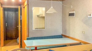Ein Zimmer mit einer hölzernen Bank, einem Sofa mit blauen Kissen, einer Pendelleuchte und einem Spiegel an der Wand.