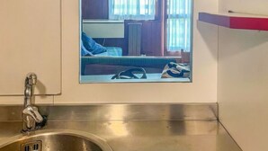 Ein modernes Badezimmer mit einem Edelstahlwaschbecken, einer Pendelleuchte und einem Fenster mit Vorhängen.