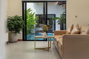 Ein Wohnzimmer mit einer Couch, einem Couchtisch und einer Topfpflanze.