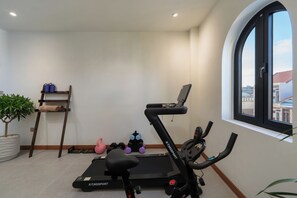 Ein Heimfitnessraum mit Laufband, Hanteln und Yogamatte.