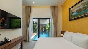 Ein Hotelzimmer mit Bett, Fernseher, Schreibtisch, einem Gemälde und Blick auf einen Außenpool.