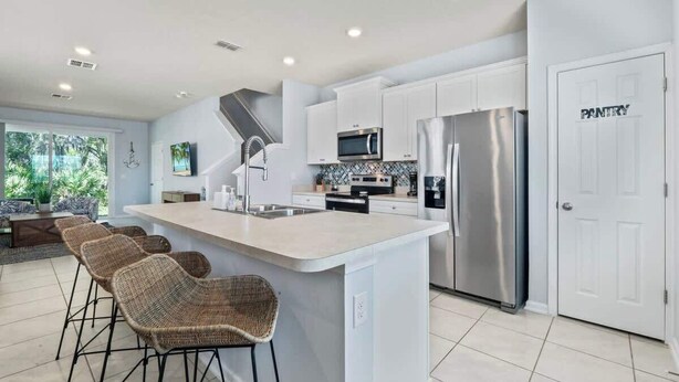 Een moderne keuken met een centraal eiland, roestvrijstalen apparatuur en een inloopkastdeur.
