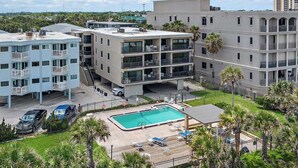Et hotel med flere etager, en swimmingpool, udendørs siddepladser og udsigt over det omkringliggende område.