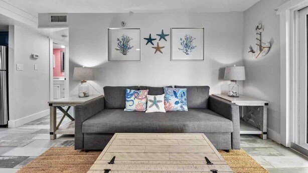 A living room with a grey sofa, framed artwork, and a coffee table.