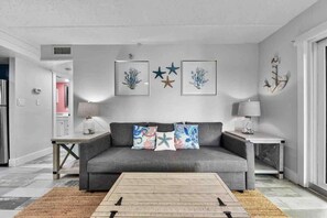 Ein Wohnzimmer mit grauem Sofa, gerahmten Kunstwerken und einem Couchtisch.