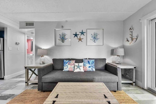 A living room with a grey sofa, framed artwork, and a coffee table.