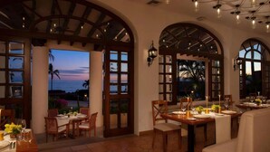 A dining area with tables set for two, large arched windows, and a view of the ocean. - Presidential 2-bedroom suite in enchanting San José del Cabo (San José del Cabo)