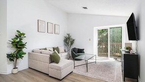 Una sala de estar con un sofá, una mesa de centro y un televisor montado en la pared.