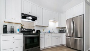Una cocina moderna con armarios blancos, electrodomésticos de acero inoxidable y piso de madera.