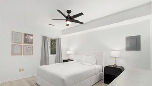 A modern bedroom with a bed, bedside tables, a ceiling fan, and framed artwork on the wall. - Lake-View Hideaway | Beaches | Wineries (Sawyer)