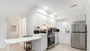 A modern kitchen with white cabinetry, stainless steel appliances, and a central island. - Lake-View Hideaway | Beaches | Wineries (Sawyer)