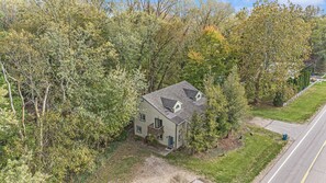 A two-story house with a gabled roof, surrounded by dense trees and a well-maintained lawn. - Lake-View Hideaway | Beaches | Wineries (Sawyer)