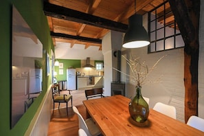 A dining area with a wooden table, chairs, a vase with branches, and a hanging light fixture. - Thatched cottage with private dike on the Elbe (Freiburg Elbe)