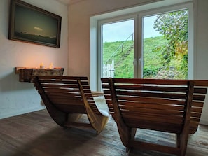 A room with two wooden benches, a painting on the wall, and a window with a view of greenery. - Thatched cottage with private dike on the Elbe (Freiburg Elbe)