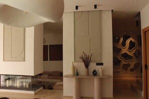 A modern interior with a fireplace, a console table with decorative items, and a unique wall design. - Villa Camelia - Breakfast and Heated Pool (Marrakech)