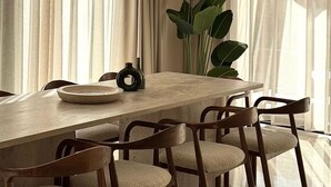 Een eethoek met een grote tafel, stoelen en een hanglamp.