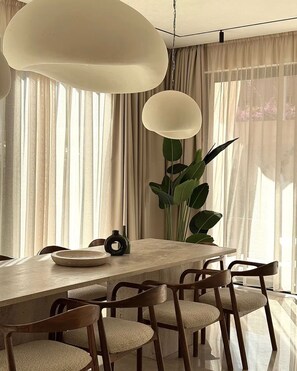 A dining area with a large table, chairs, and a hanging light fixture. - Villa Camelia - Breakfast and Heated Pool (Marrakech)
