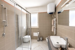 Ein modernes Badezimmer mit einer Duschkabine, einer weißen Toilette, einem Waschbecken mit Spiegel und einem Handtuchhalter.