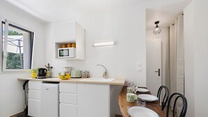 Una cucina moderna con lavastoviglie integrata, un tavolo da pranzo in legno con sedie e una finestra che lascia entrare luce naturale.