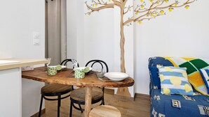 Zona pranzo con tavolo in legno, sedie e un affresco raffigurante un albero di limoni.