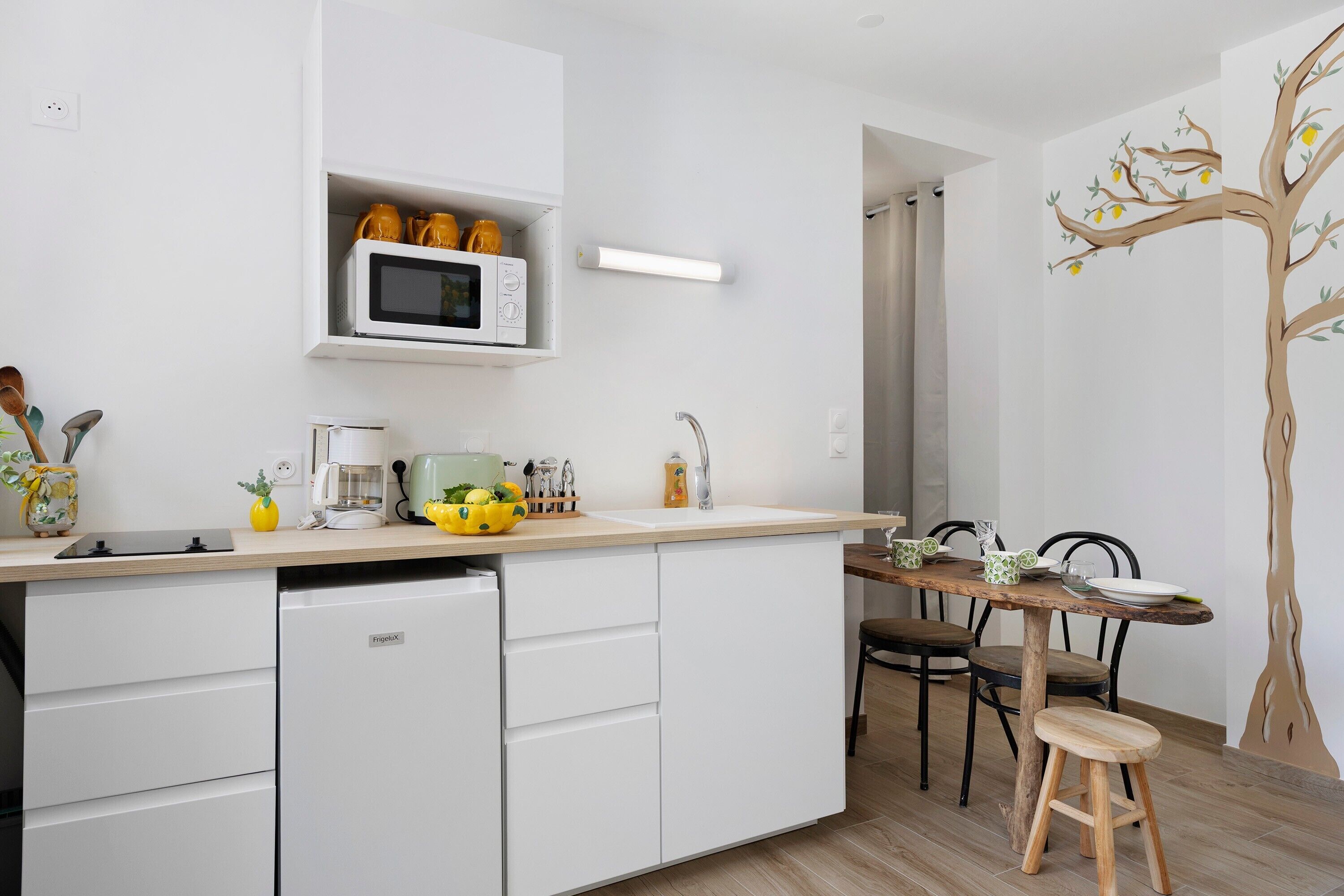 Una cucina con forno a microonde, macchina del caffè e zona pranzo con tavolo e sedie.