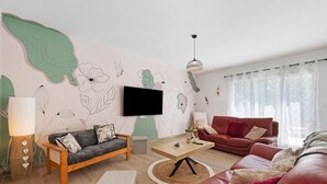 A living room with a sofa, a coffee table, a TV, and a lamp. - Holiday Home “L'Or du Temps” with Private Terrace, Garden and Wi-Fi (Froidfond)