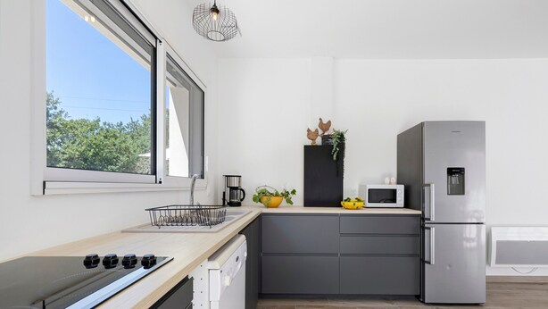 A modern kitchen with a built-in stove, a microwave, and a stainless steel refrigerator. - Holiday Home “L'Or du Temps” with Private Terrace, Garden and Wi-Fi (Froidfond)