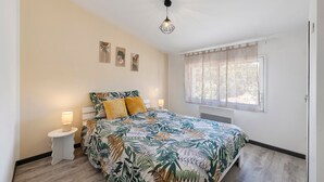 A bedroom with a bed, bedside tables, a window with curtains, and wall art. - Holiday Home “L'Or du Temps” with Private Terrace, Garden and Wi-Fi (Froidfond)