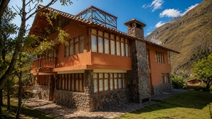 Una casa de dos pisos construida en piedra y madera, con ventanas grandes y un balcón.