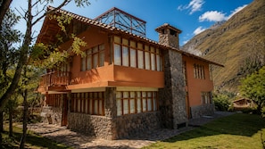 A two-story house with stone and wood construction, large windows, and a balcony. - Casa del Pisonay (family-friendly—up to 14 people, your nature retreat, Arin) (Calca)