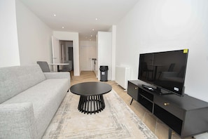 A modern living room with a sofa, a round coffee table, a TV, and a black entertainment unit. - Modern & Bright 1BED Apartment in Leeds - Sleeps 3 (Leeds)