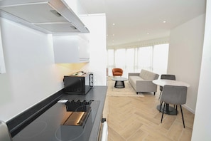 A modern kitchen with a built-in stove and a dining area with a round table and chairs. - Modern & Bright 1BED Apartment in Leeds - Sleeps 3 (Leeds)